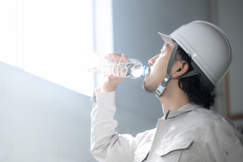 夏季休工とならない現場で水分補給を行う作業員